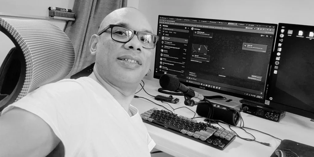 Juan Domínguez, actual fundador de Sonoterapia Nicaragua, en su etapa anterior como Ingeniero de Infraestructura y DevOps. La imagen le muestra en su estación de trabajo con múltiples monitores, ilustrando el entorno de alta presión y monitoreo de alertas que le llevó a buscar el bienestar a través del sonido.