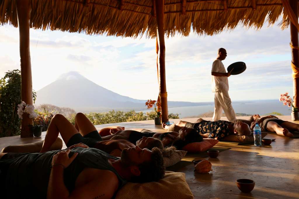 Fotografía de un grupo de participantes durante una sesión de cacao y relajación sonora al aire libre frente al volcán Maderas.