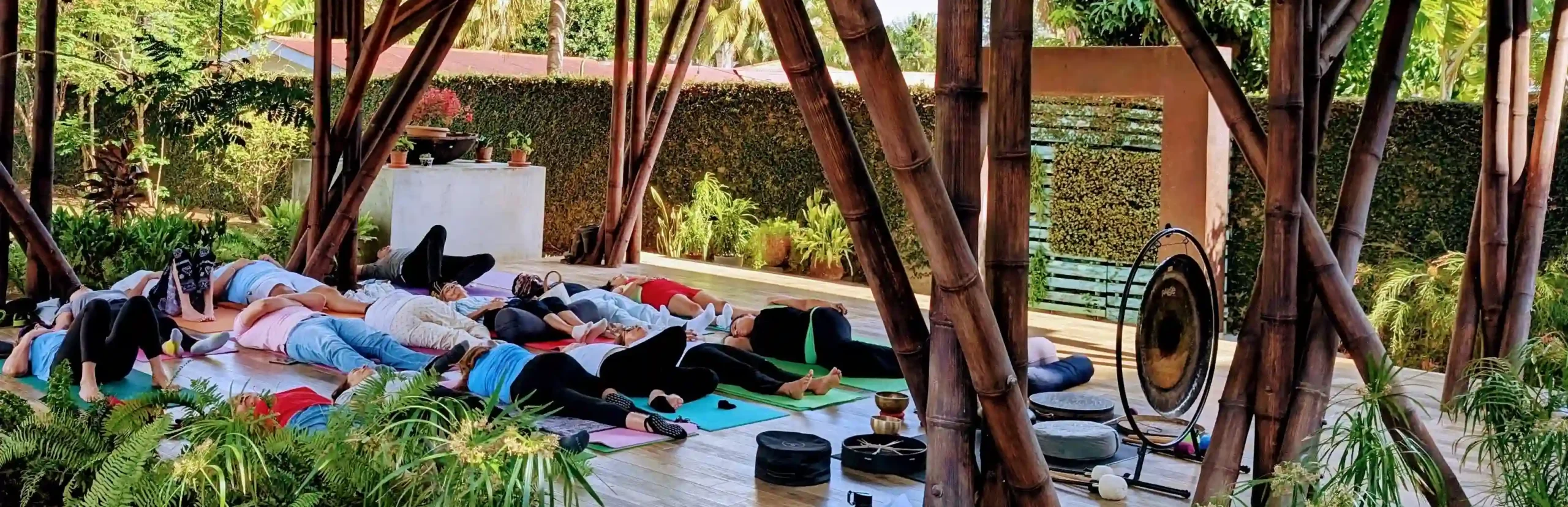Esta imagen muestra un grupo de personas participando en una sesión de baño de sonido y meditación al aire libre en una terraza