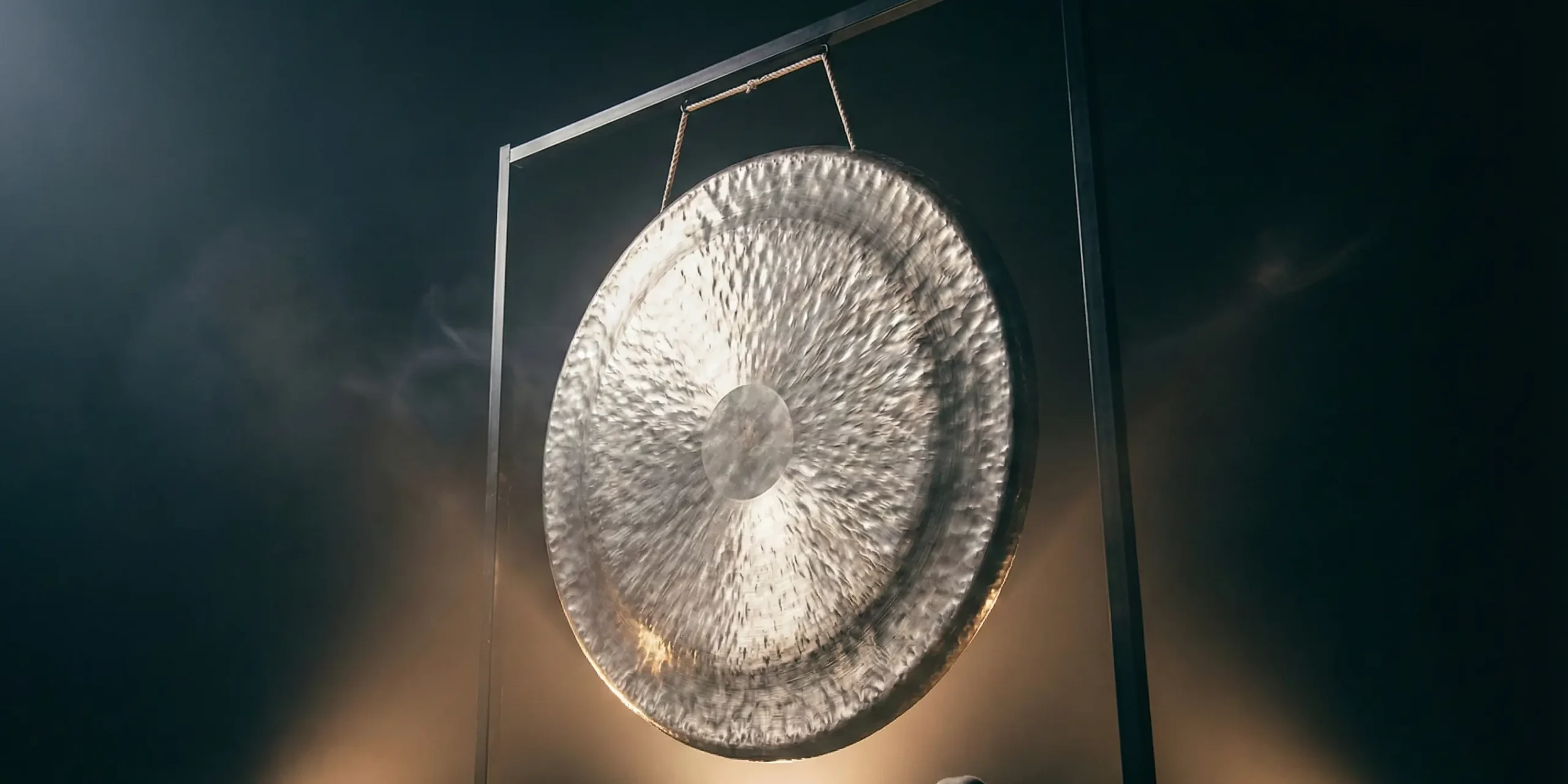 Gong de nikel y plata en el centro de escenario fondo oscuro luces al centro