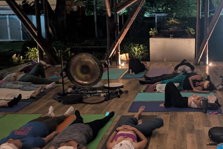 Baño de gong nocturno al aire libre, participantes recostados alrededor del gong